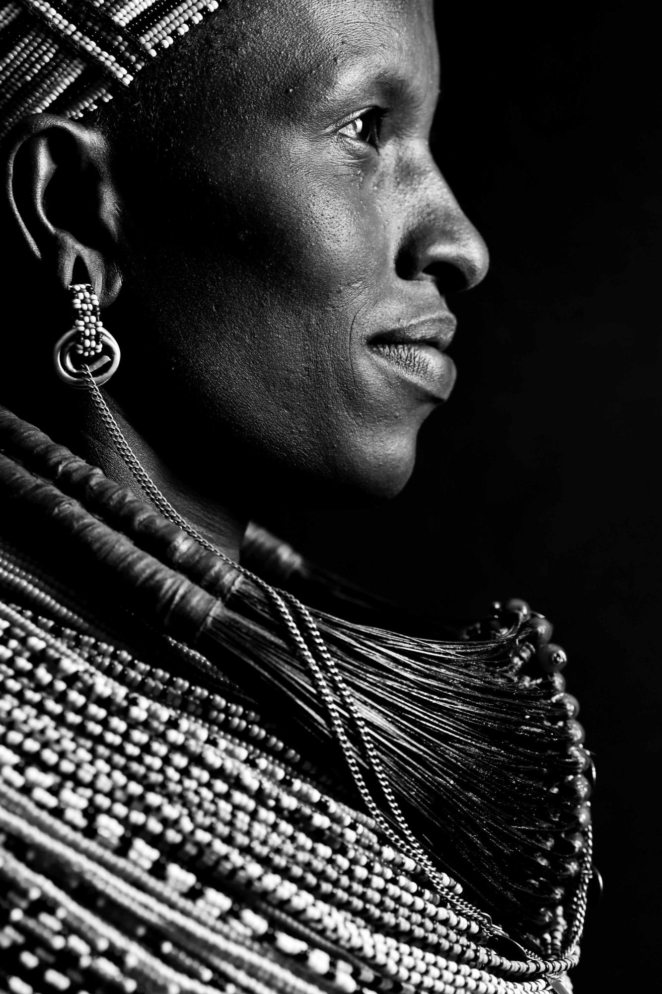 A close up of the profile of a Samburu woman in traditional dress