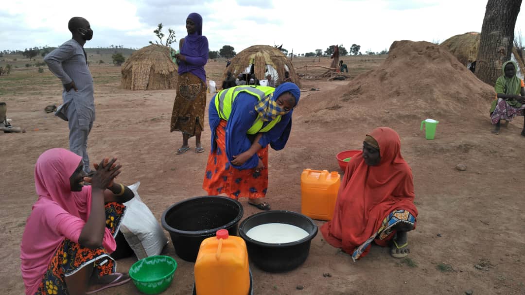 A group of women stand over containers filled with milk
