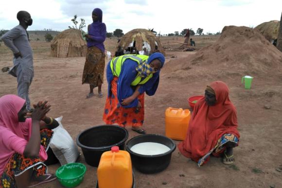 A group of women stand over containers filled with milk