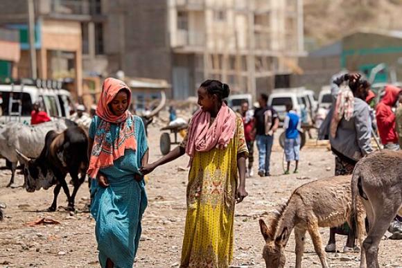 Two smiling women talk as they walk towards the camera