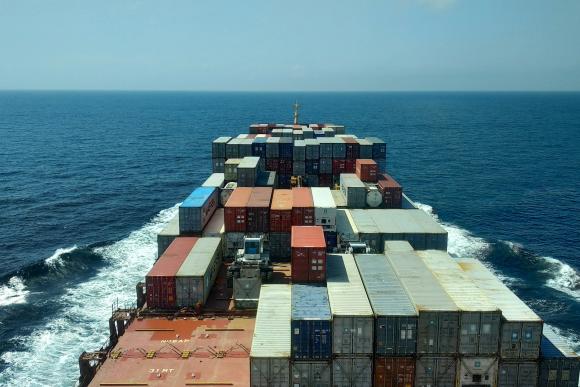 Close up image of a cargo ship with containers and the sea in the background