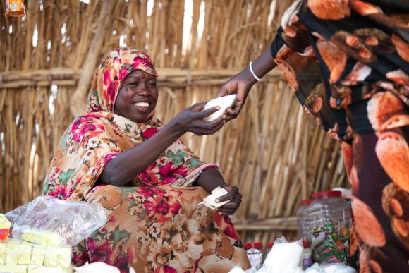 A woman smiles as she exchanges goods in a market