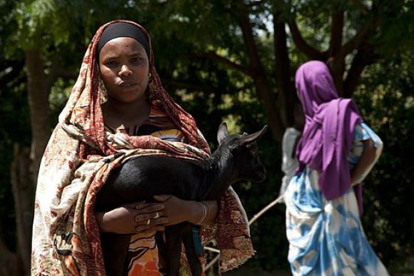 A close up of a woman carrying a goat