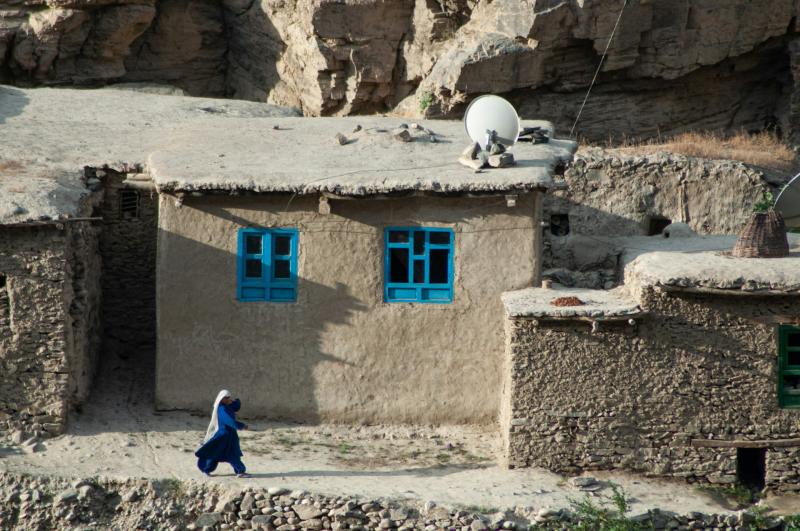 A woman walks past a house in a village