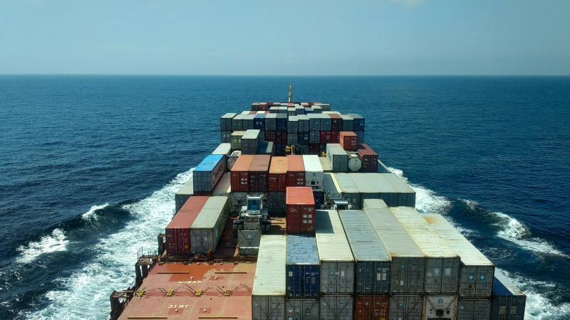 Close up image of a cargo ship with containers and the sea in the background