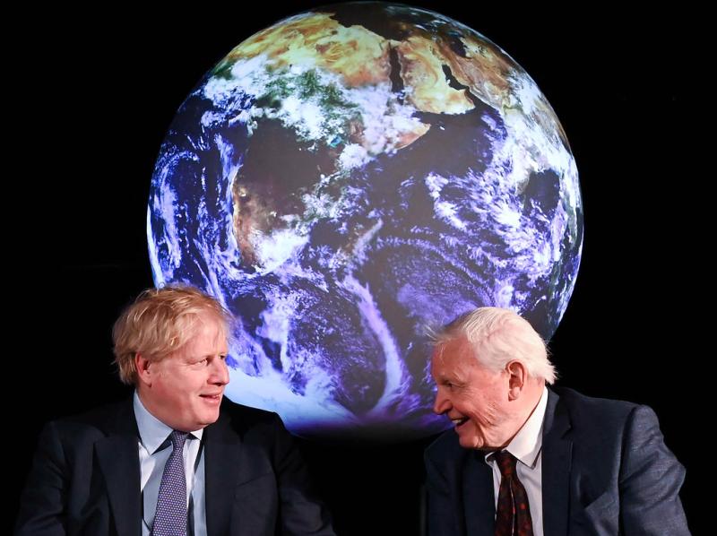 Two men seated in front of an image of planet Earth