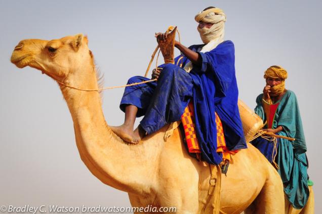 Tuareg man shelters from the sun in the Sahara desert, Mali.