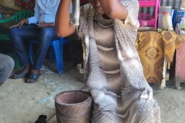 A woman pounds ginger with a pestle and mortar