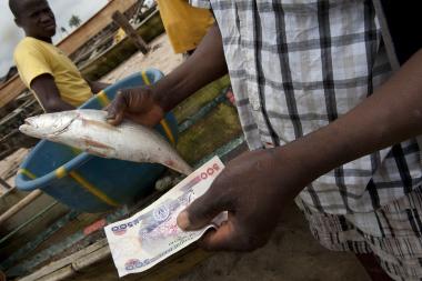 A man holds a fish in one hand and some money in the other