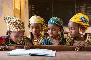 Young girls share a textbook in class in Makalondi, Tilaberri Region, Niger.