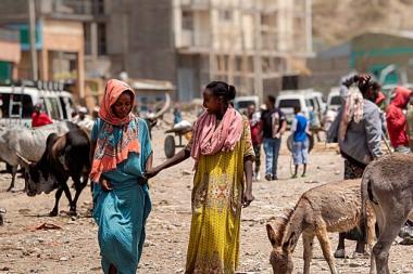 Two smiling women talk as they walk towards the camera