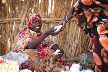 A woman smiles as she exchanges goods in a market
