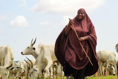 A smiling woman herding cattle